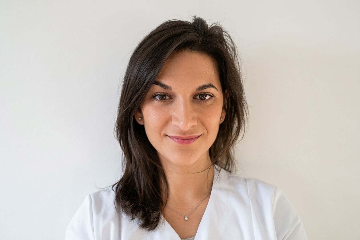Déborah Levy, ostéopathe, en tenue de soin blanche, sourit face à l’objectif.