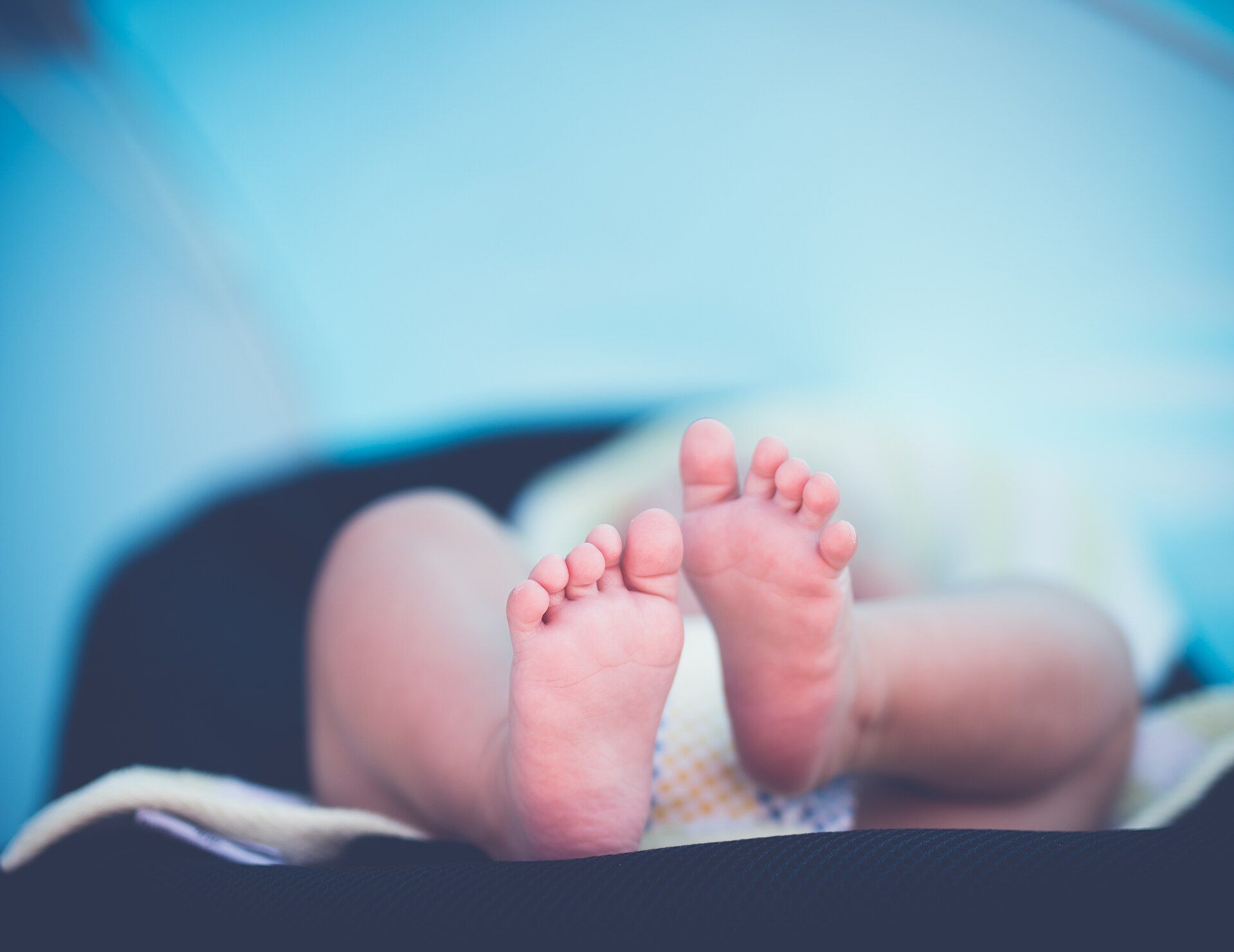 Les pieds d'un nouveau-né, allongé sur une couverture.